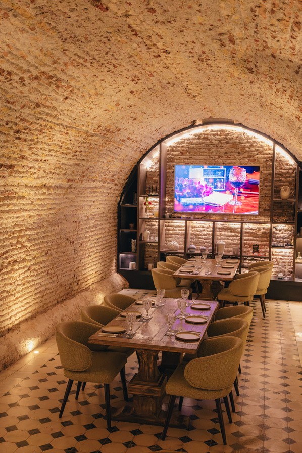 Salón colonial de Tito Bravo con arco de piedra y mesas para compartir